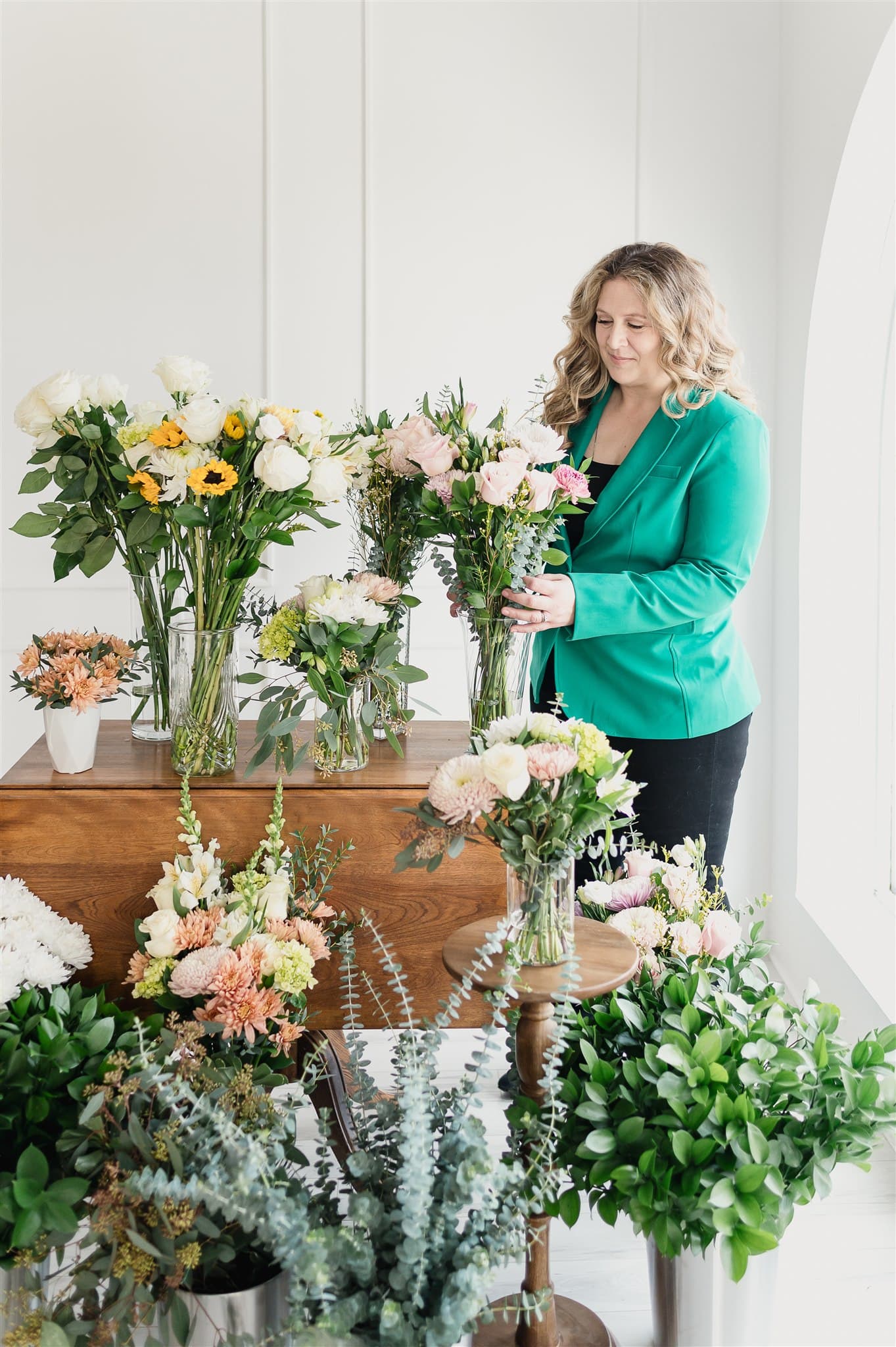 Christine, fondatrice de BeauBlooms, compose un bouquet au milieu de ses arrangements floraux