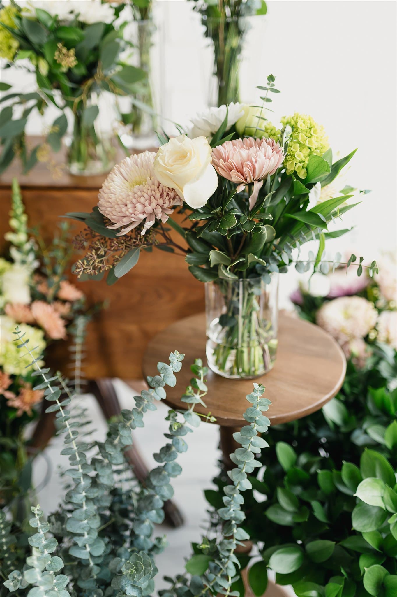Bouquet BeauBlooms sur un guéridon en bois, entouré d'eucalyptus