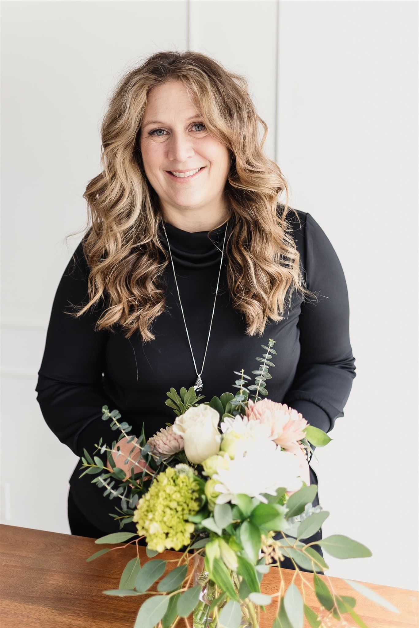 Portrait de Christine, fleuriste et fondatrice de BeauBlooms, derrière un bouquet